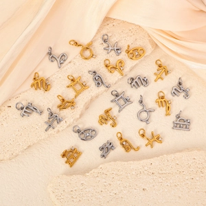 Detailed view of 24k gold and silver zodiac pendants with zircons on textured stone