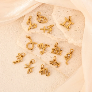 24k gold plated stainless steel zodiac pendants with zircon stones on stone background