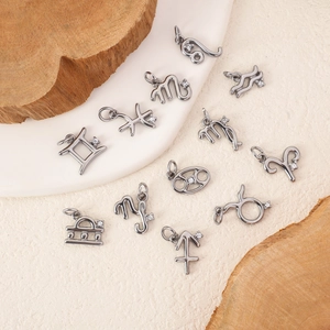 24k plated stainless steel zodiac pendants set with rhinestones on a natural wooden background