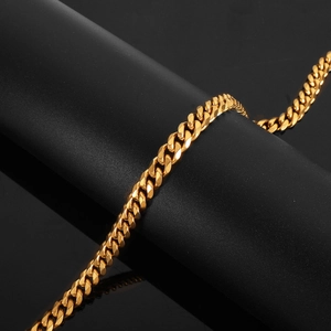 Polished gold Cuban link chain necklace for men and women on a sleek black background