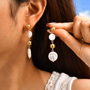 Close-up of vintage gold-plated drop earrings with pearls worn by a model
