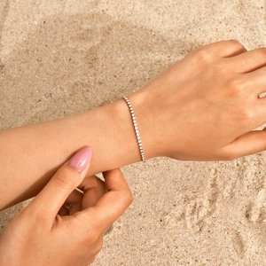 Nahaufnahme eines 18K vergoldeten Tennisarmbands mit Zirkonia am Handgelenk eines Models
