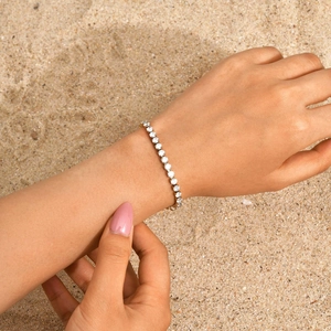 Makroaufnahme eines funkelnden Tennisarmbands mit Zirkonia an einem Model am Strand