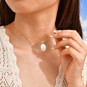 Women's gold stainless steel necklace featuring an oval pearl pendant on a crochet top