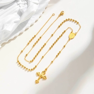 Détail du collier chapelet doré avec médaille de la Vierge Marie et croix sur fond blanc