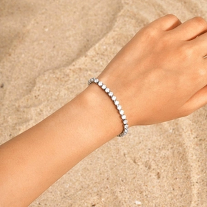 Nahaufnahme eines silbernen Tennisarmbands mit Zirkonia auf einem Strandhintergrund