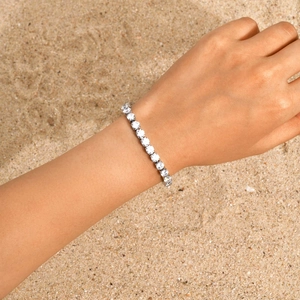 Nahaufnahme eines silbernen Tennisarmbands mit Zirkonia, getragen am Handgelenk am Strand