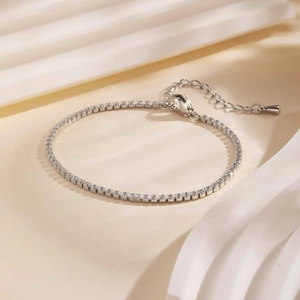 Detail eines silbernen Tennisarmbands mit Zirkonia-Steinen auf Seidenstoff