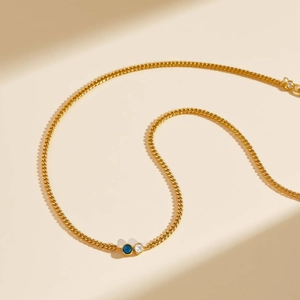 Dettaglio della collana in acciaio dorato con pendenti in zircone blu e bianco lucido