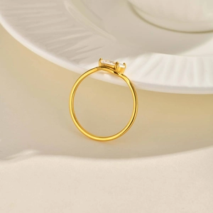 Gros plan d'une bague dorée en acier inoxydable avec deux zircons sur un plateau blanc