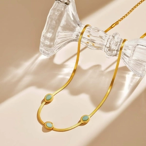 Dettaglio della collana a catena serpente dorata con tre pietre ovali turchesi su vetro