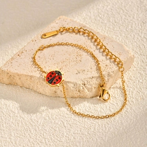 Detail van vergulde roestvrijstalen kinderarmband met rode emaille lieveheersbeestje