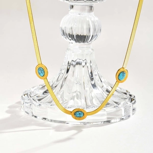 Dettaglio della collana a catena serpente dorata con tre pietre turchesi su base di vetro