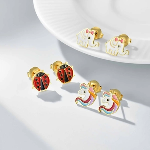 Detail shot of gold children's earring set featuring enamel elephant, ladybug and unicorn