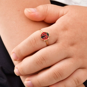Close-up of a delicate gold ladybug ring featuring vibrant red and black enamel detail