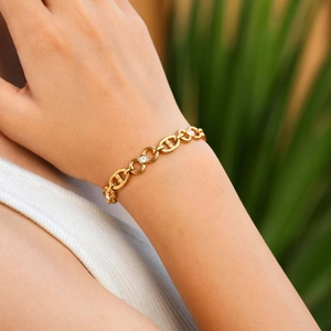 Detail of gold chain bracelet with D-rings and zircon circles on a female wrist