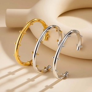 Primer plano detallado de brazaletes de acero pulido en forma de C con cuentas
