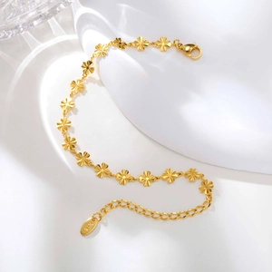 Dettaglio di un bracciale a fiori dorati con incisione K18 sulla maglia regolabile