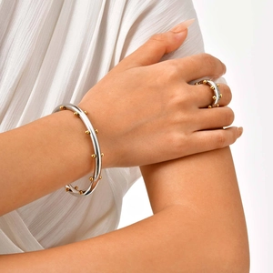 Detalle de conjunto de brazalete y anillo plateado con cuentas doradas usado por modelo