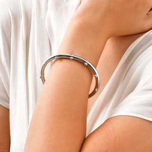 Vista detallada de brazalete plateado con cuentas geométricas en la muñeca