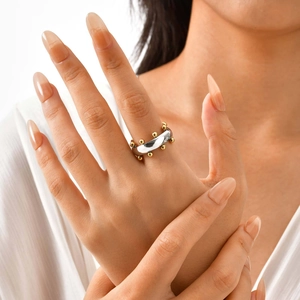 Primer plano de un anillo de acero plateado con detalles de cuentas doradas