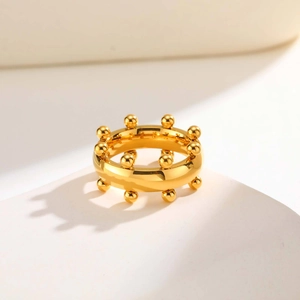 Anillo geométrico dorado pulido con bolas minimalistas en soporte blanco moderno