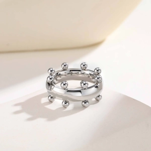 Primer plano de un anillo de acero inoxidable plateado con cuentas esféricas y pulido