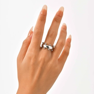 Primer plano de un anillo de acero inoxidable plateado con cuentas en el dedo de una modelo