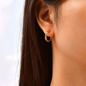 Close-up of stylish U-shaped gold hoop earring worn on ear with polished finish