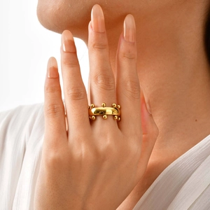 Bague large chic en acier inoxydable doré avec accents de perles sur le doigt d'un modèle