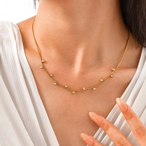 Gold plated snake chain necklace with round white zircon stones on female model