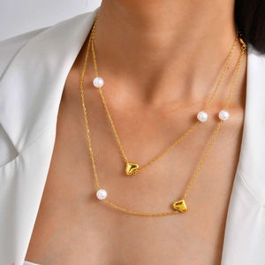 Collier double couche doré avec pendentifs cœur et perles blanches sur un mannequin
