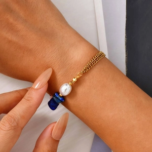 Détail du bracelet double chaîne dorée avec perle et pierres de lapis-lazuli bleues