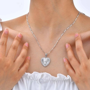Gros plan d'un collier cœur Vierge Marie en argent avec zircon porté par un modèle