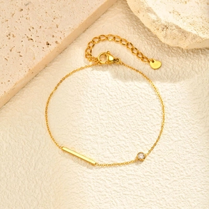 Bracelet doré en acier inoxydable avec barre, zircon et breloque cœur sur fond de pierre