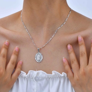 Gros plan du pendentif Vierge Marie et chaîne Figaro portés par un mannequin en blanc
