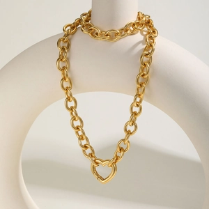 Detailansicht einer goldenen groben Gliederkette mit Herz-Karabinerverschluss auf Requisiten