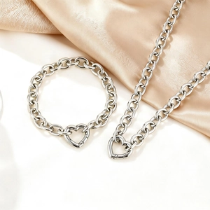 Detail von silbernem Halsketten- und Armbandset mit Herzverschluss auf Satin