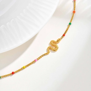 Detailed close-up of golden snake bracelet featuring colorful enamel beads on a thin chain