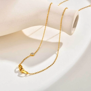Détail du collier doré avec pendentifs ovales entrelacés et accent de zircon scintillant