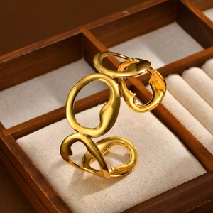 Golden geometric hollow open bangle with intertwined organic rings on a jewelry box