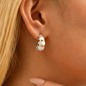 Boucles d'oreilles créoles en acier doré avec émail blanc sur un mannequin femme