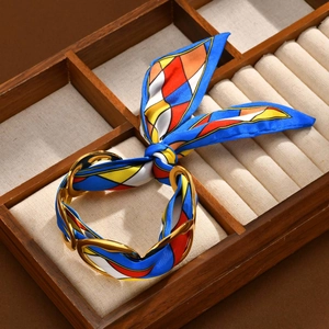 Detailed shot of golden chain bracelet with blue floral silk scarf in jewelry box