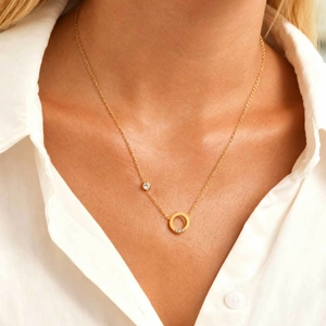 Collier en acier doré avec pendentif anneau serti de zircons porté par une femme