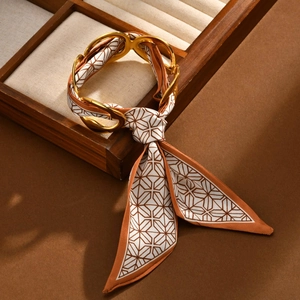 Detail of gold-plated geometric chain bracelet with brown silk fabric scarf weaving