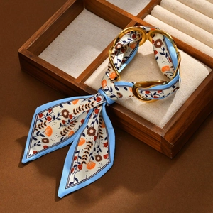 Detail of silk scarf bracelet with floral pattern and polished gold metal rings