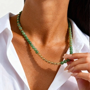 Close-up of beaded stone necklace with emerald green beads and gold stainless steel balls