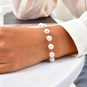 Elegant gold chain bracelet with large white pearls worn on a woman's wrist