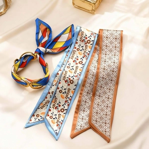Detail of elegant satin twilly scarves featuring floral and geometric patterns with a gold buckle