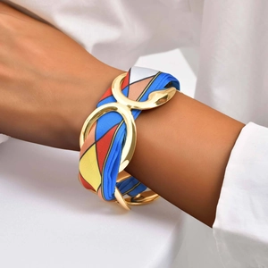 Detail of gold geometric hollow cuff bracelet with vibrant silk ribbon weaving